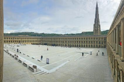 The Piece Hall courtyard in Halifax with its surrounding colonnades and a church spire beyond.